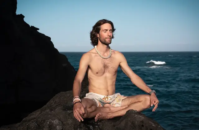 alt="a man meditating near the sea"